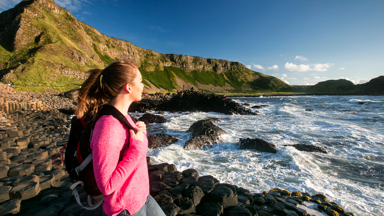 Visitor with a backpack standing on the Grand Causeway, taking in the breath-taking views